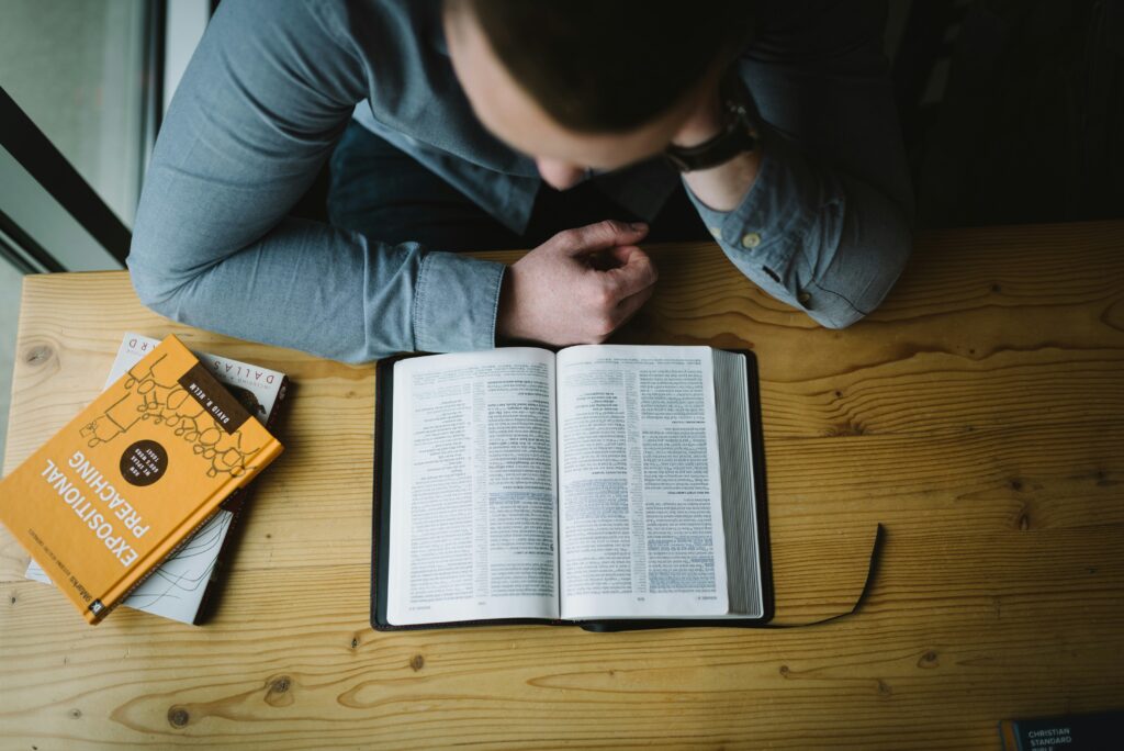 A man reading the Bible and drawing closer to God. Photo by Alexander Michl
