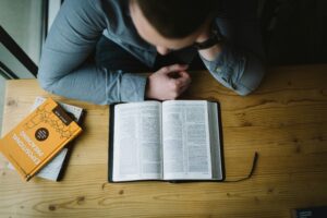 A man reading the Bible and drawing closer to God. Photo by Alexander Michl
